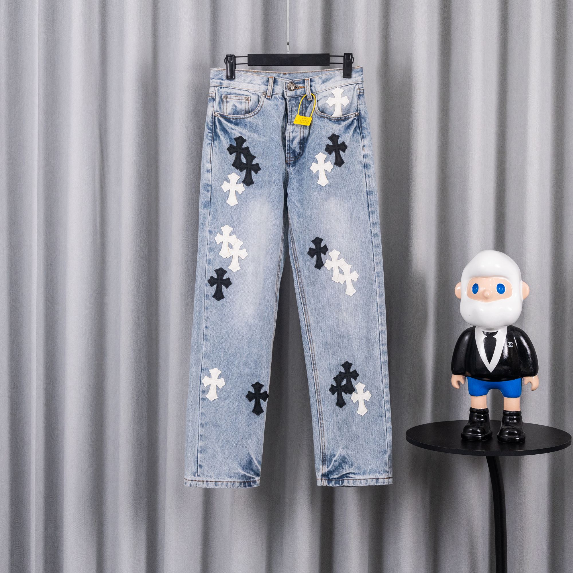 Light blue denim jeans with black and white cross patches.
