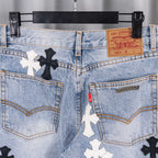 Light blue denim jeans close-up: back pockets with cross patches and label.
