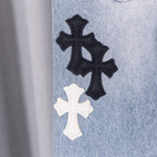 Black and white cross patches on light blue denim jeans leg.