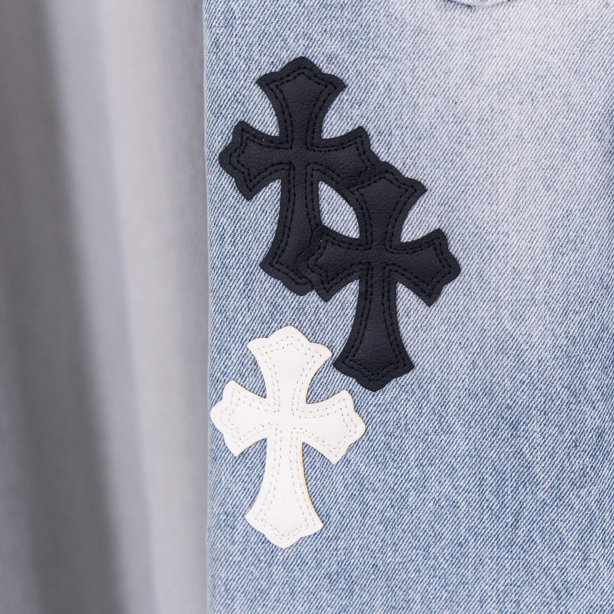 Black and white cross patches on light blue denim jeans leg.