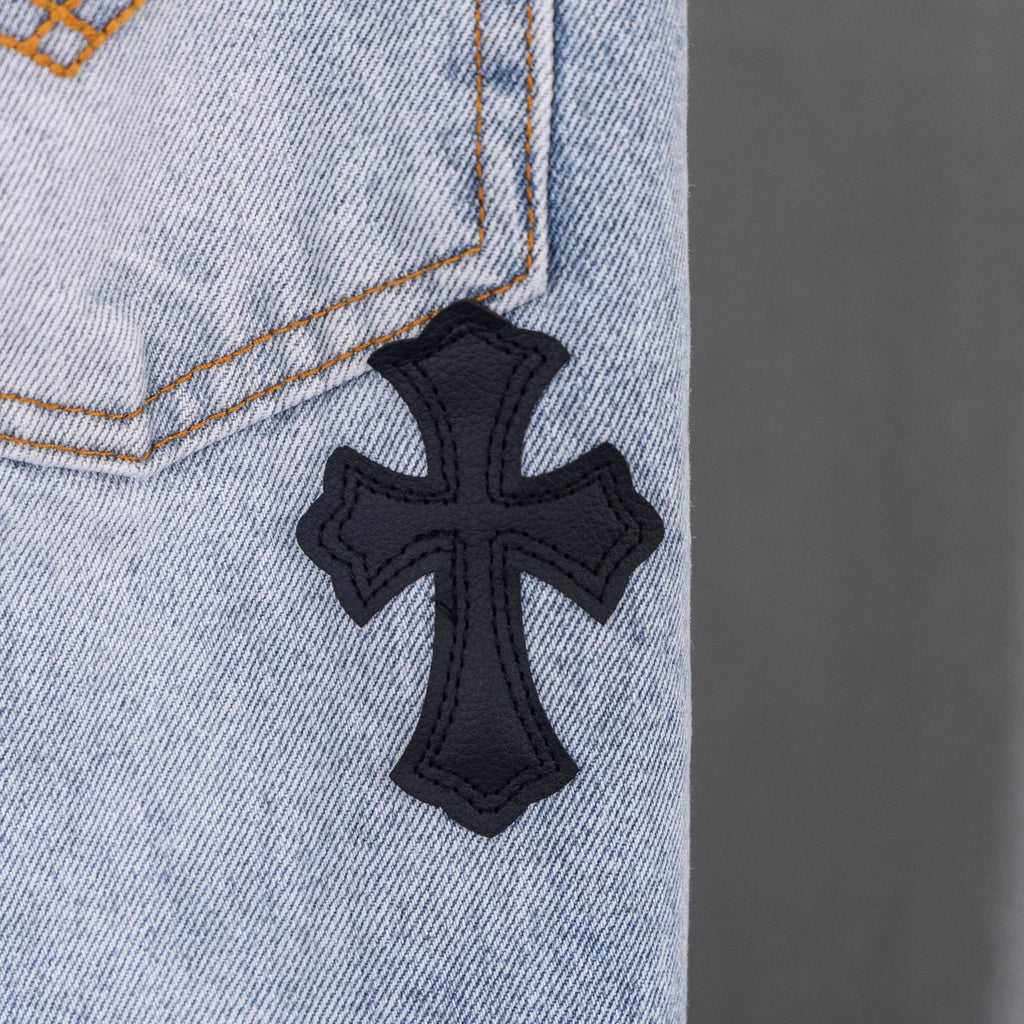 Black cross applique on light blue denim jeans.