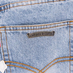 Light blue denim jeans close-up: stitched yoke with back logo patch.