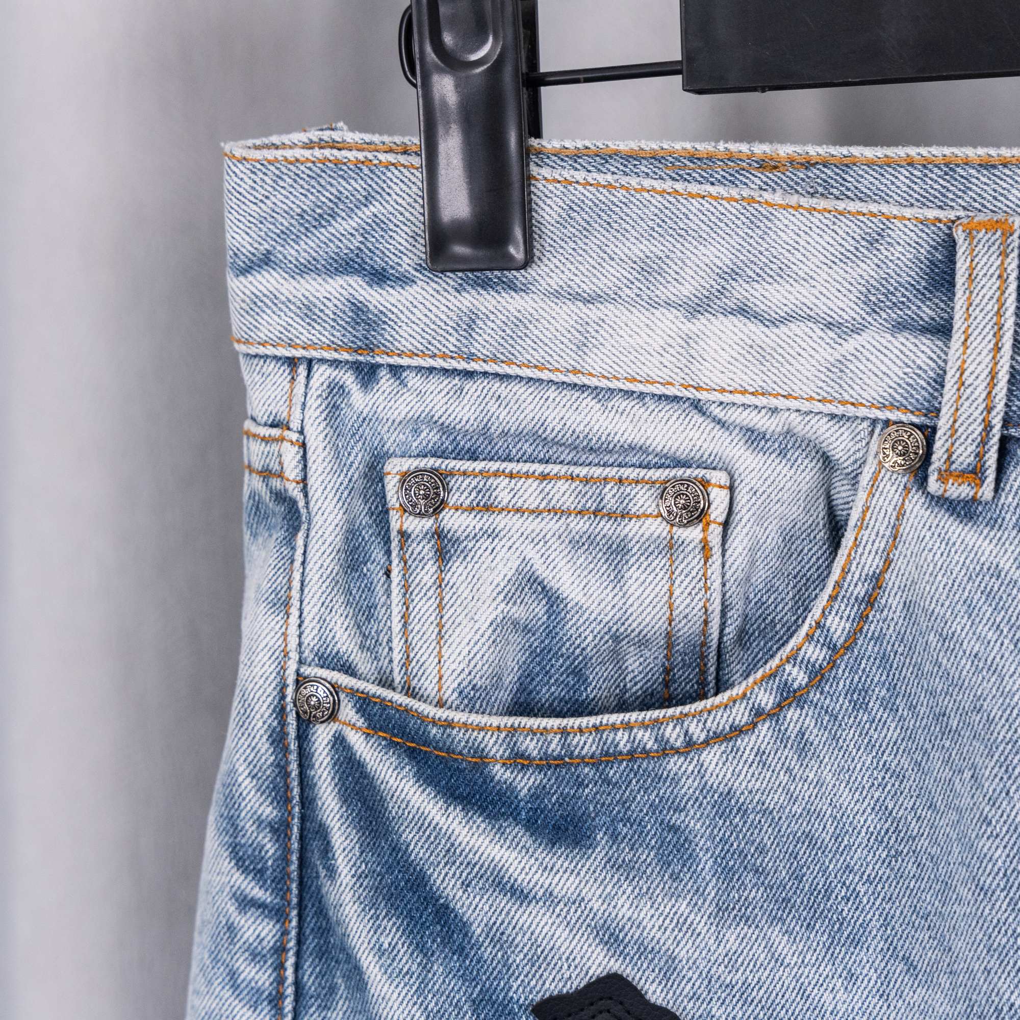 Light blue denim jeans close-up: front pocket and stitching details.
