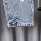 Light blue denim pants cuff with frayed hem and orange stitch detail