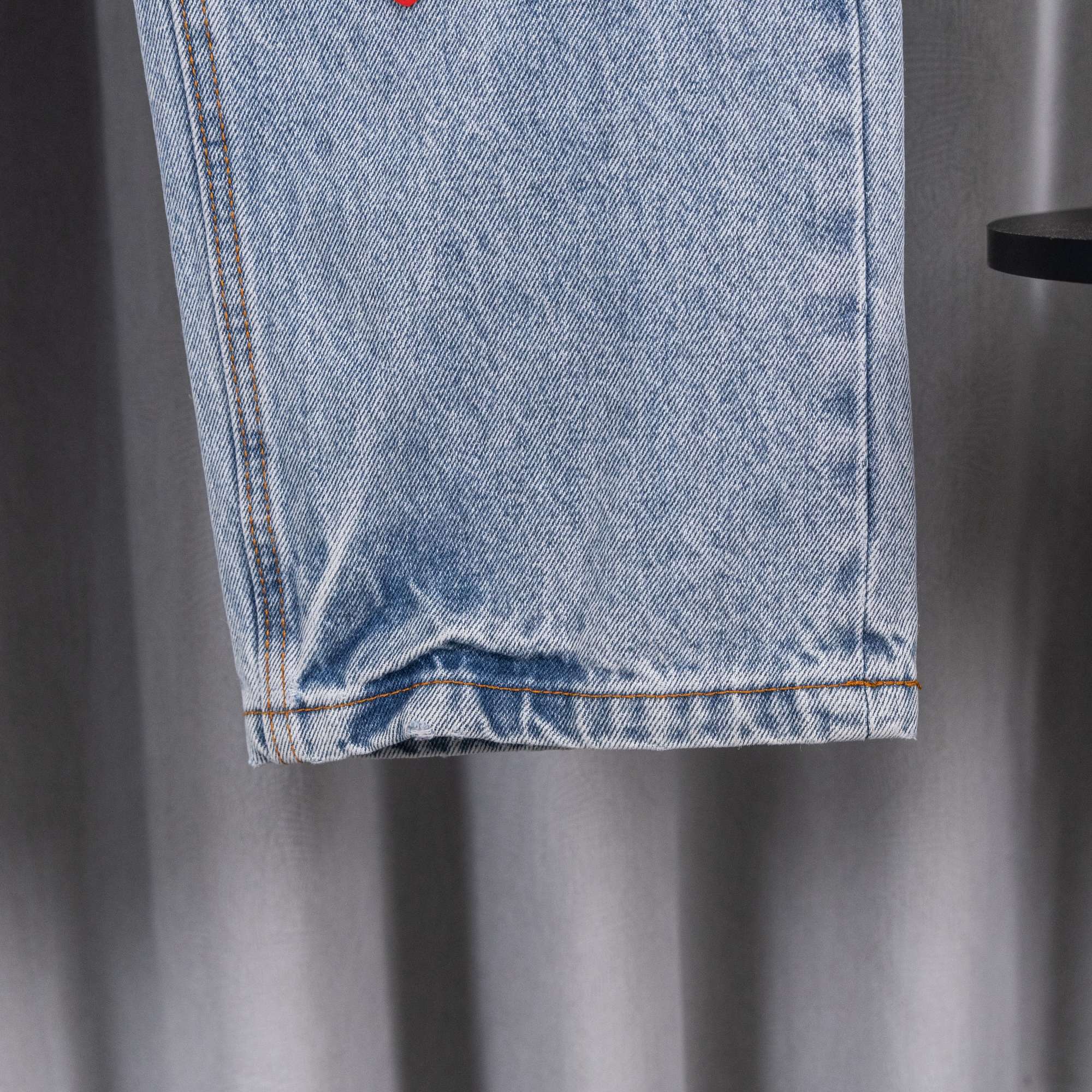 Light blue denim pants with folded hem and orange contrast topstitching