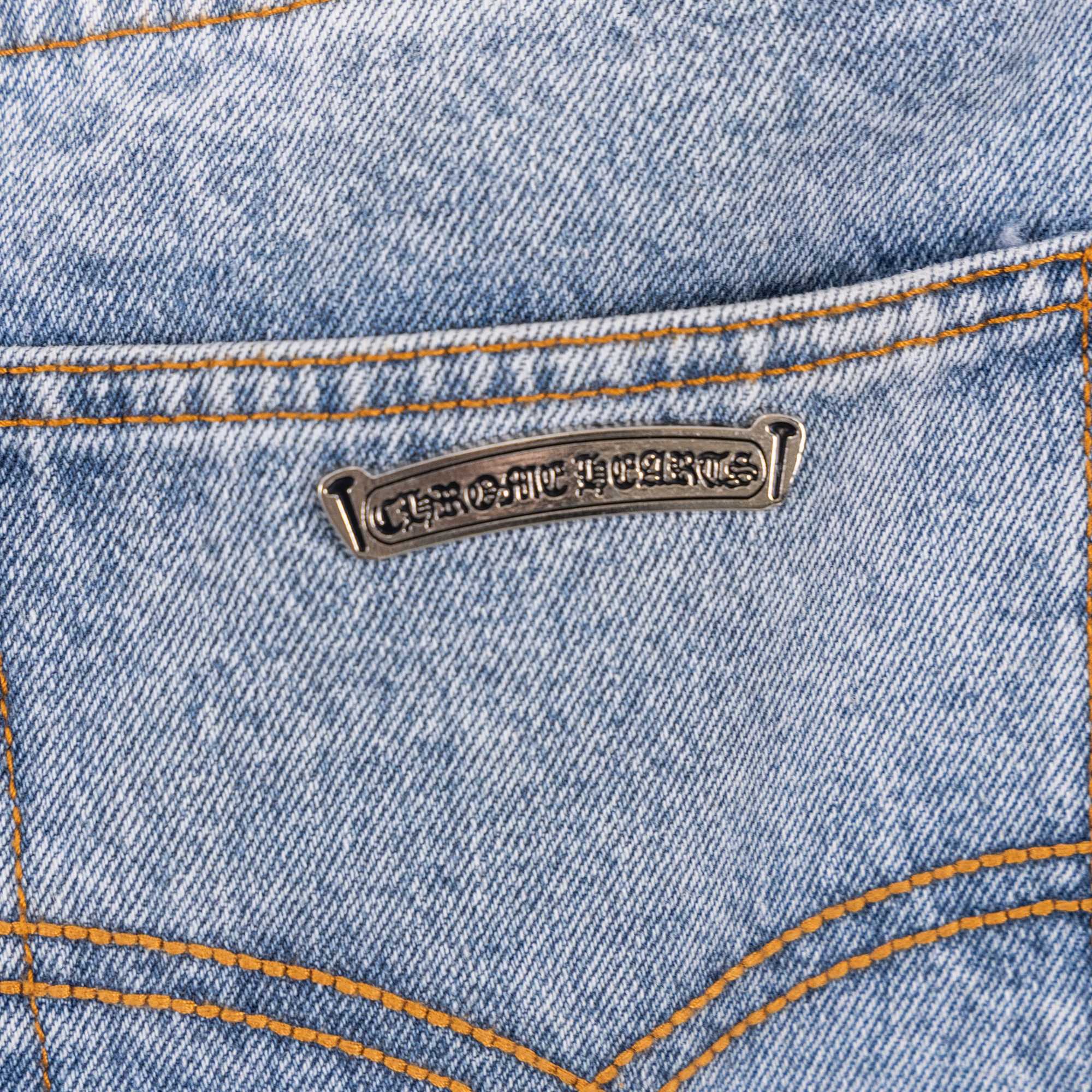 Light blue denim pants with metal logo patch and orange contrast topstitch