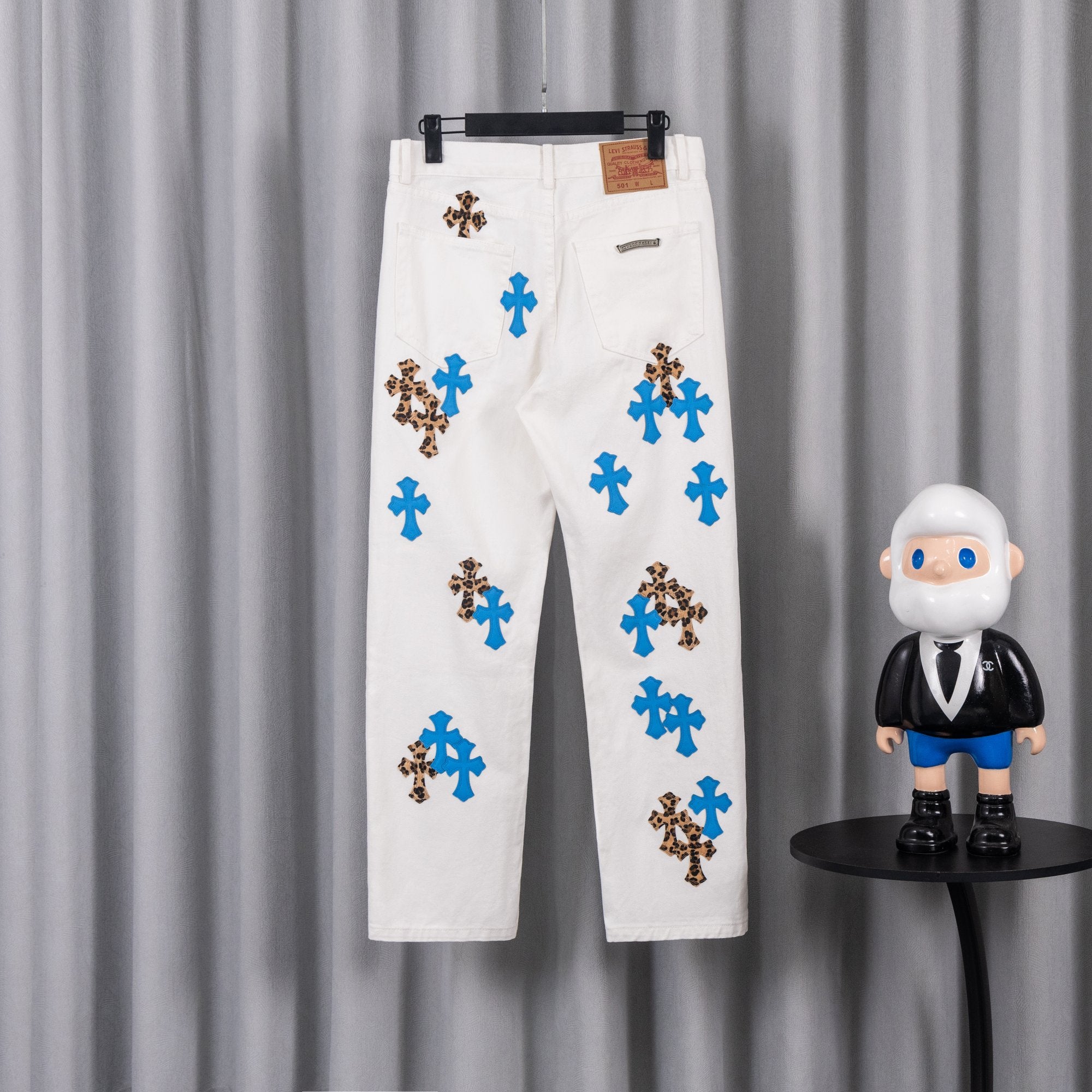 White pants with blue and leopard cross appliques, side view