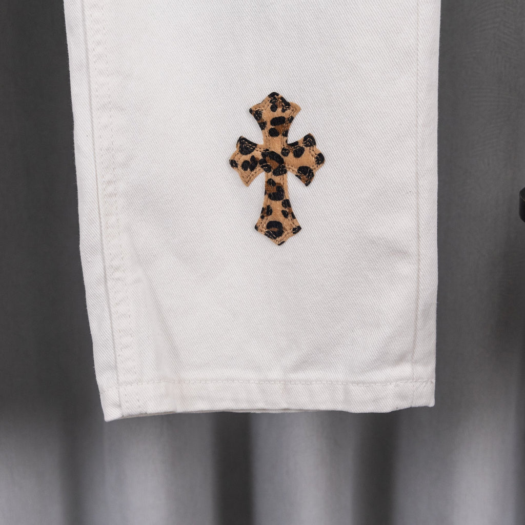 White pants cuff with leopard cross applique patch, lower-leg close-up