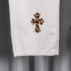 White pants cuff with leopard cross applique patch, lower-leg close-up