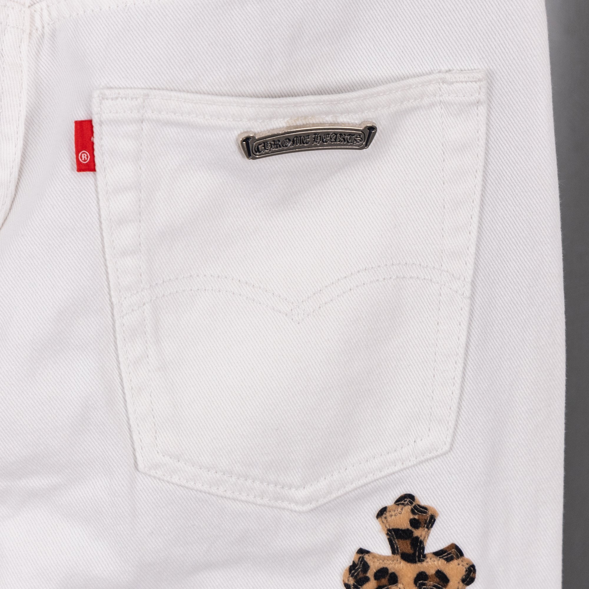 White denim pocket with small metal logo patch and leopard cross detail