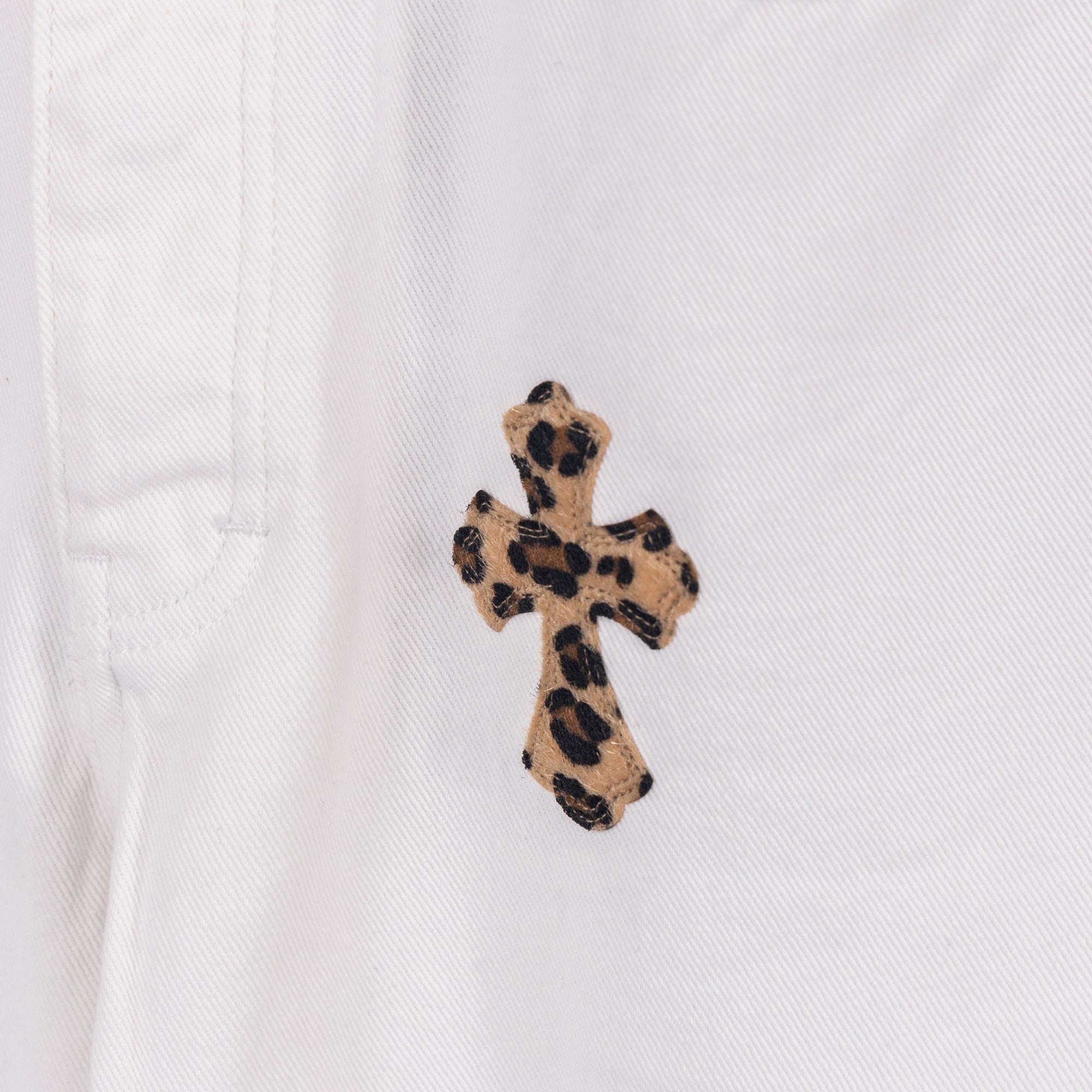 Leopard print embroidered cross patch on white denim