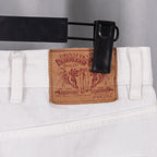 White denim pants waistband with leather logo patch and metal button hardware