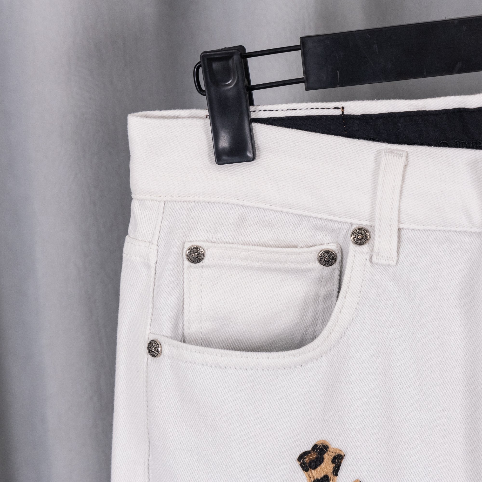 White denim pants front pocket with metal buttons and small leopard cross patch