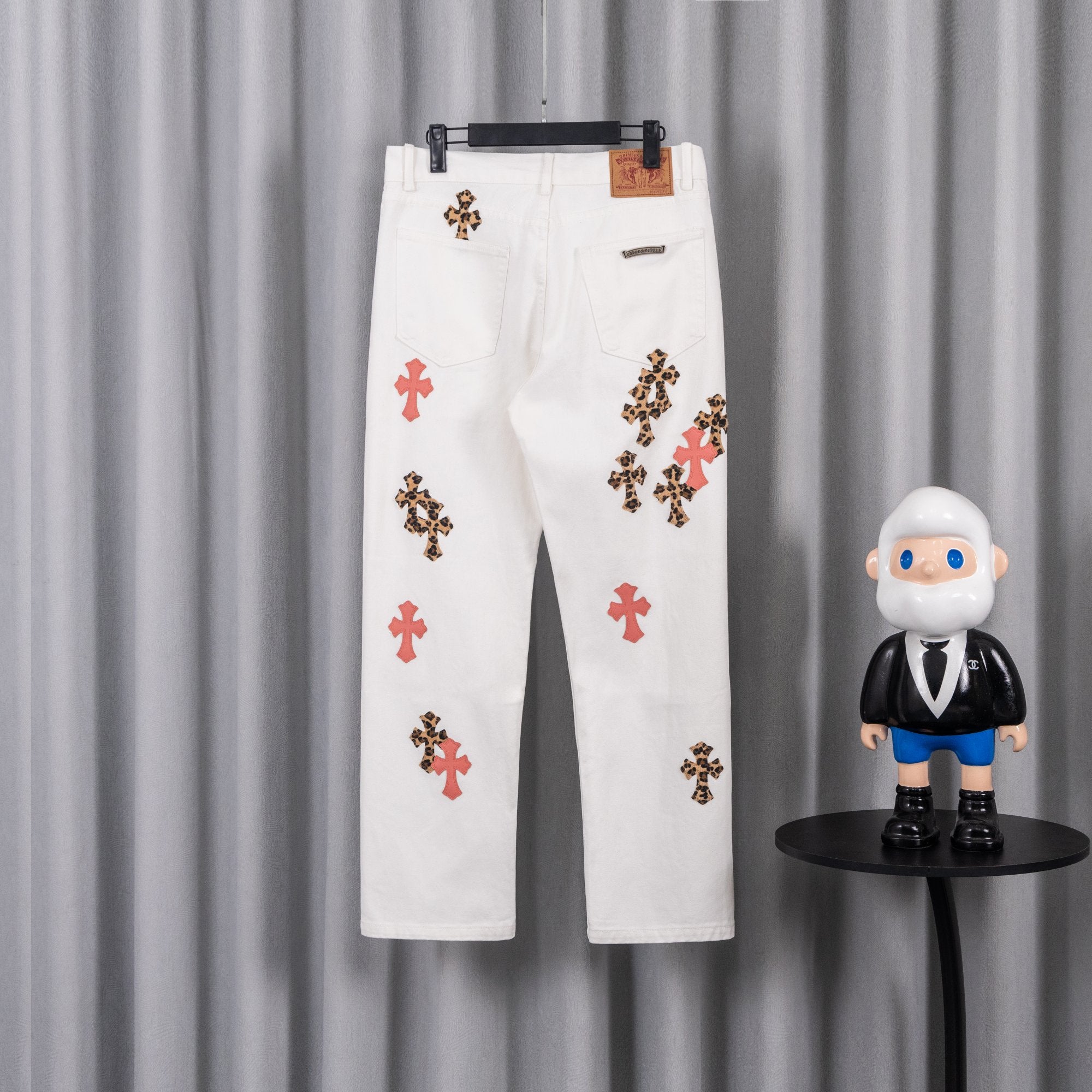 White denim pants with leopard and red cross patches, button fly