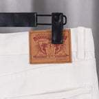 White denim pants with leather-look brand patch at waistband