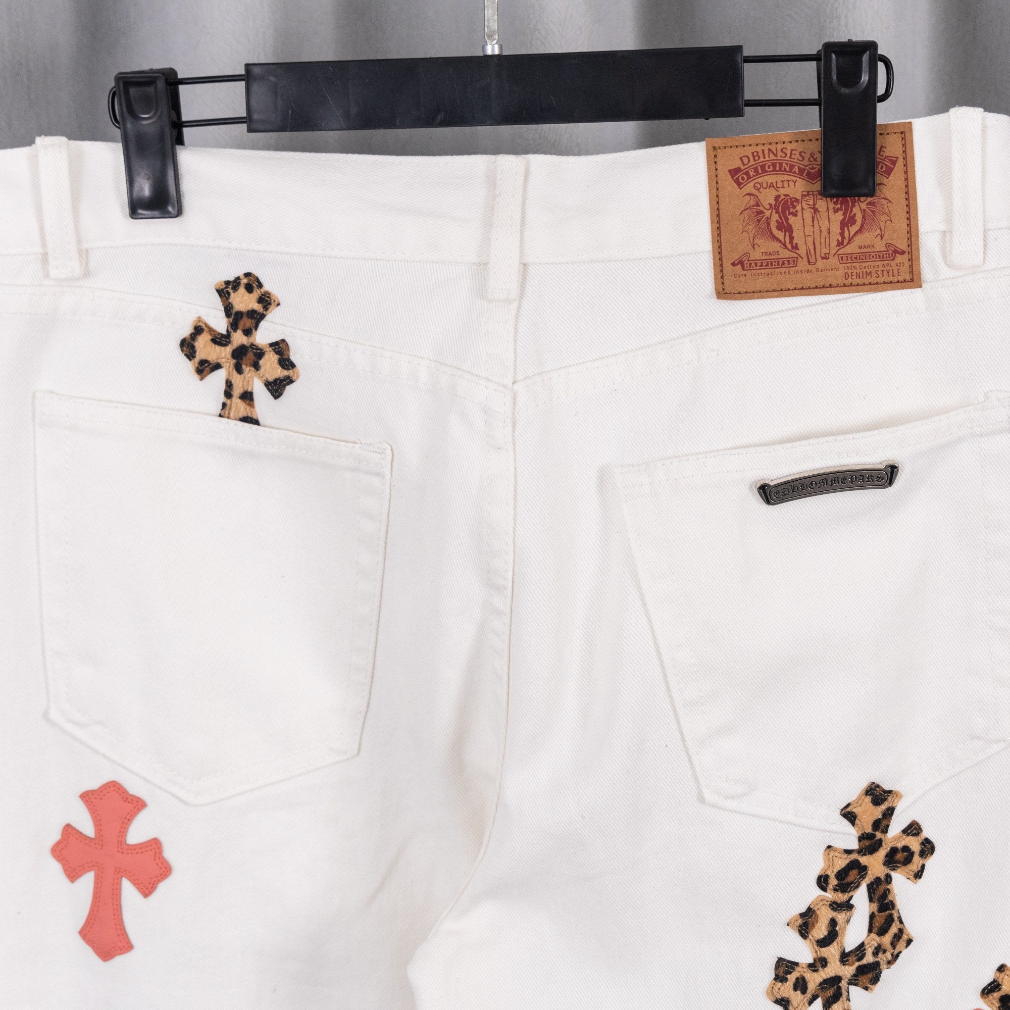 White denim pants with front pockets and embroidered cross patches