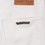 White denim pants with black logo patch and leather waist label