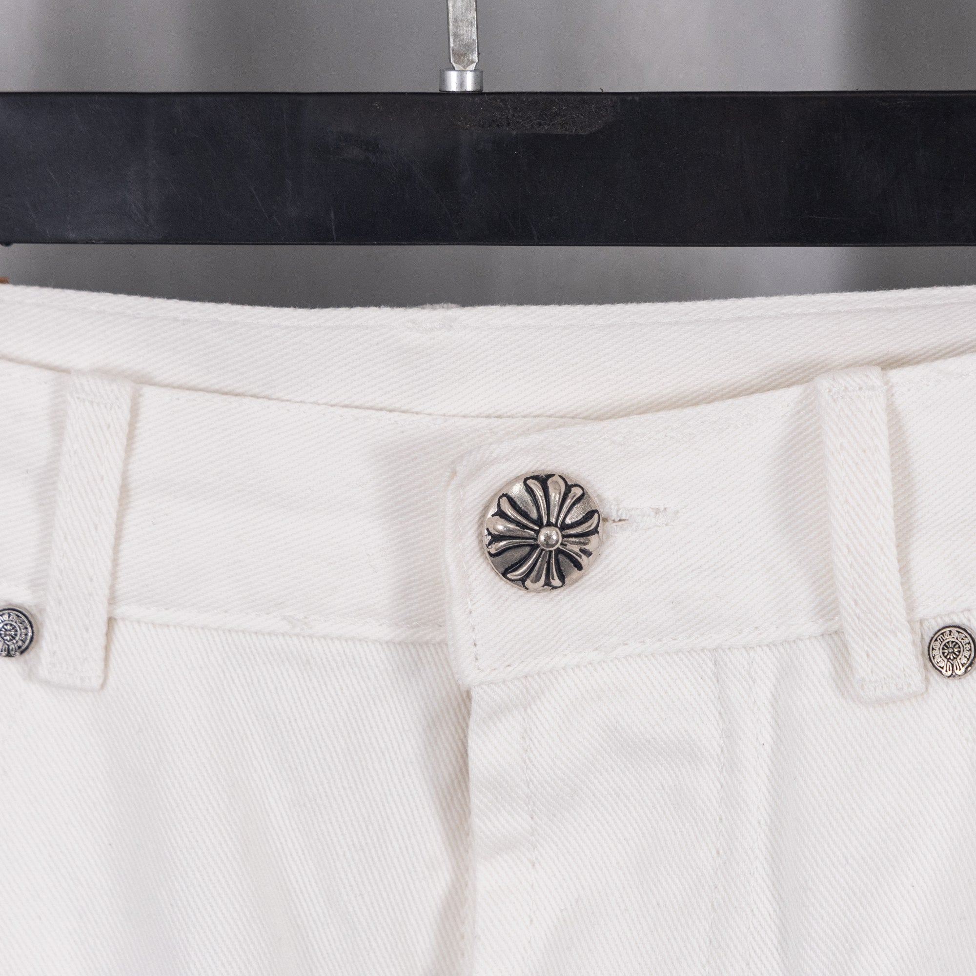 White denim pants with decorative stud button on waistband