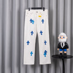 White denim pants with blue cross graphic print, front view on hanger