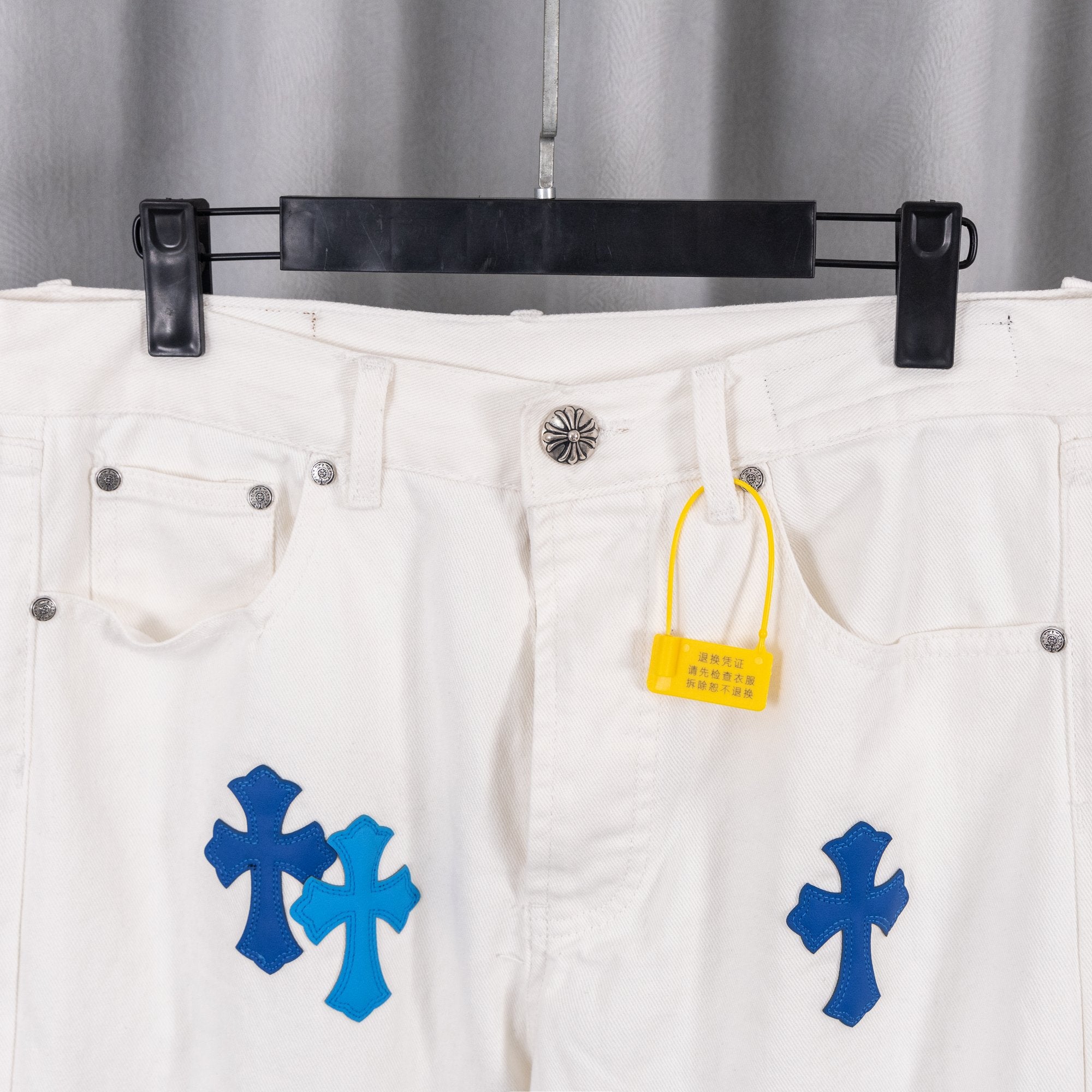 White denim pants with blue cross print, waist detail with yellow tag