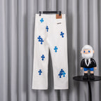 White denim pants with blue cross graphic print, back view on hanger