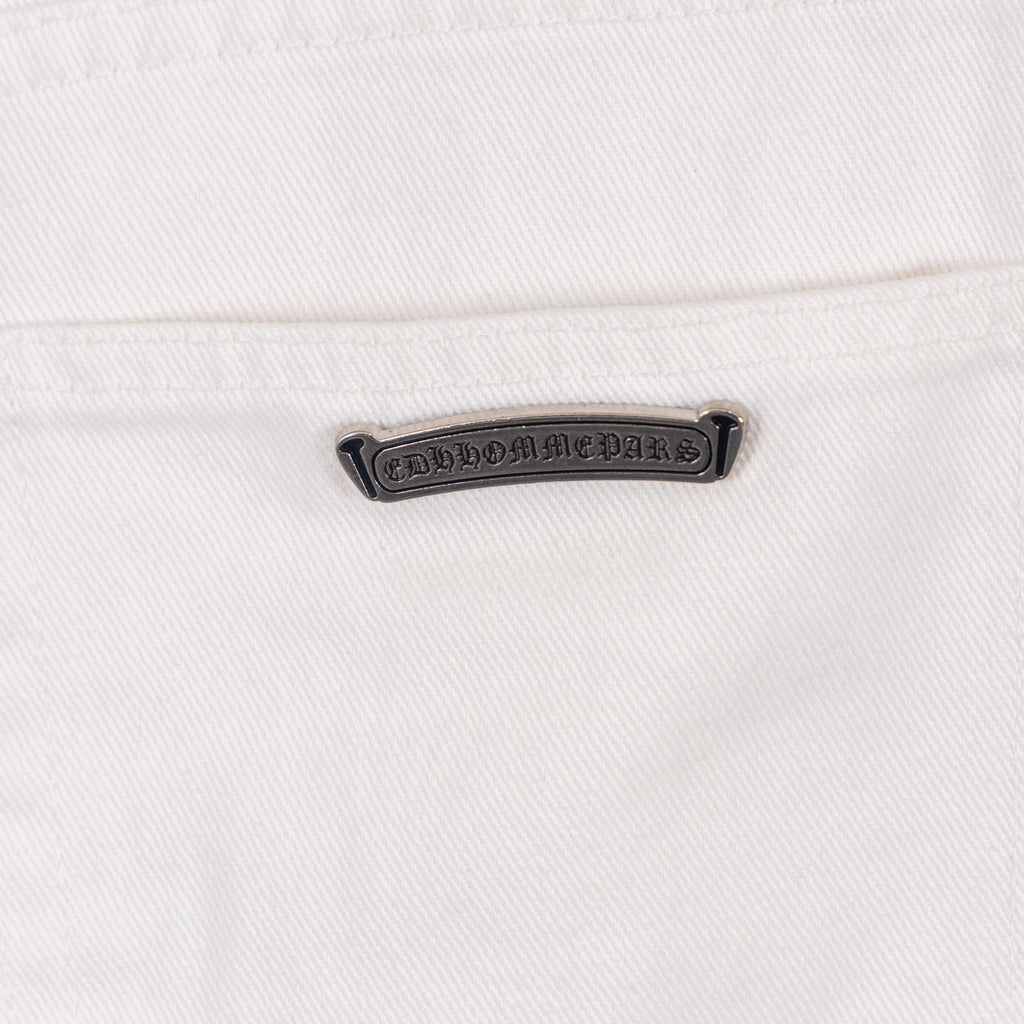 White denim pants with embossed logo label patch at waistband, close-up