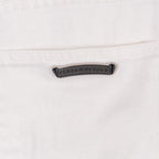 White denim pants with embossed logo label patch at waistband, close-up