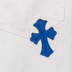 White denim pants with blue cross patch embroidery, close-up on thigh