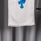 White denim pant leg hem with blue cross patch, partial view