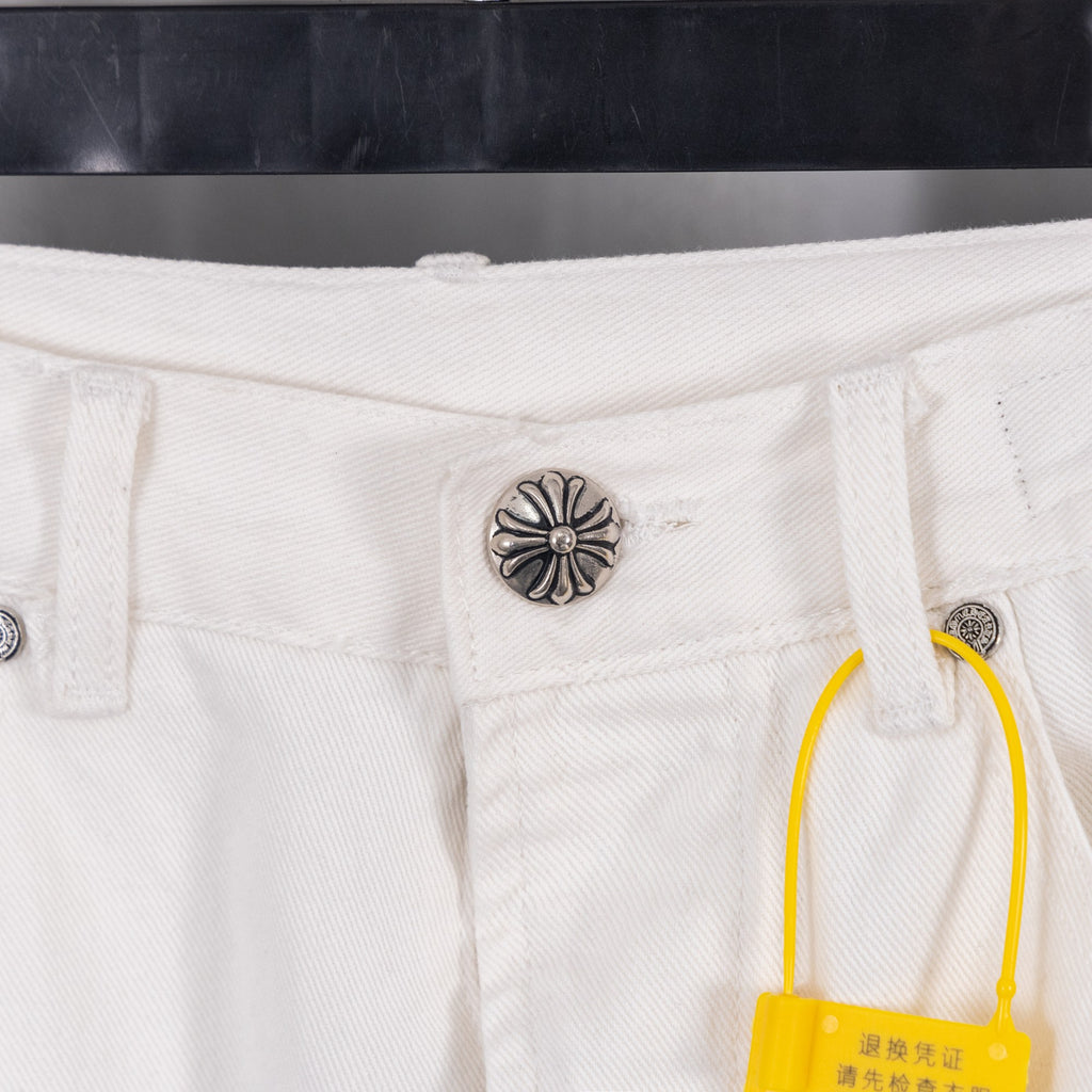 White denim pants with metal button and yellow brand tag, close-up