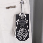 White denim pants with hang tag and decorative patch at waist, close-up