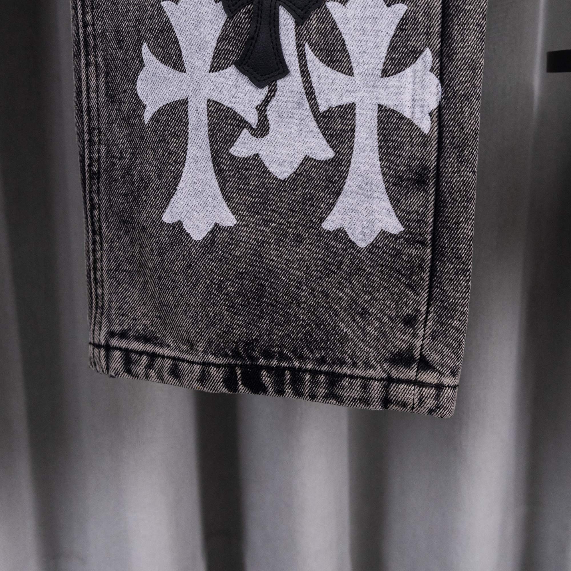 Dark gray denim jeans with large white clover-like print near the hem