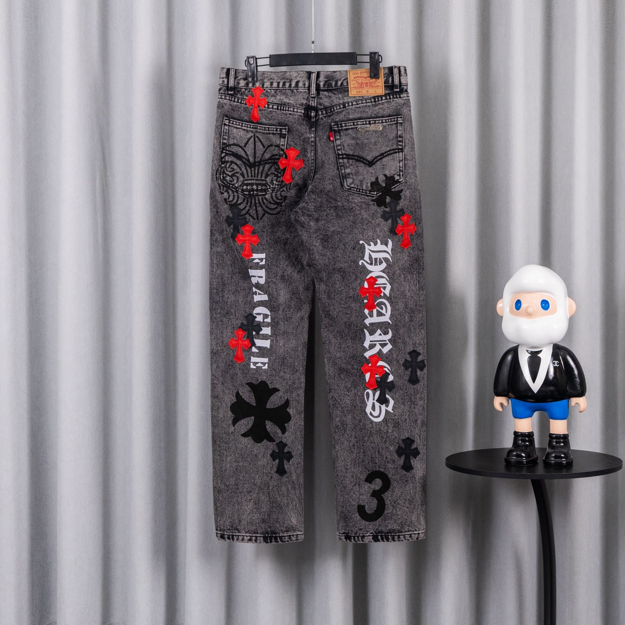 Dark gray denim jeans with red cross accents and black mirrored graphic on front