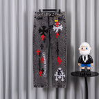 Dark gray denim jeans with red cross and black floral graphic on front legs