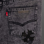 Dark gray denim jeans with stitched waistband pocket and black floral applique