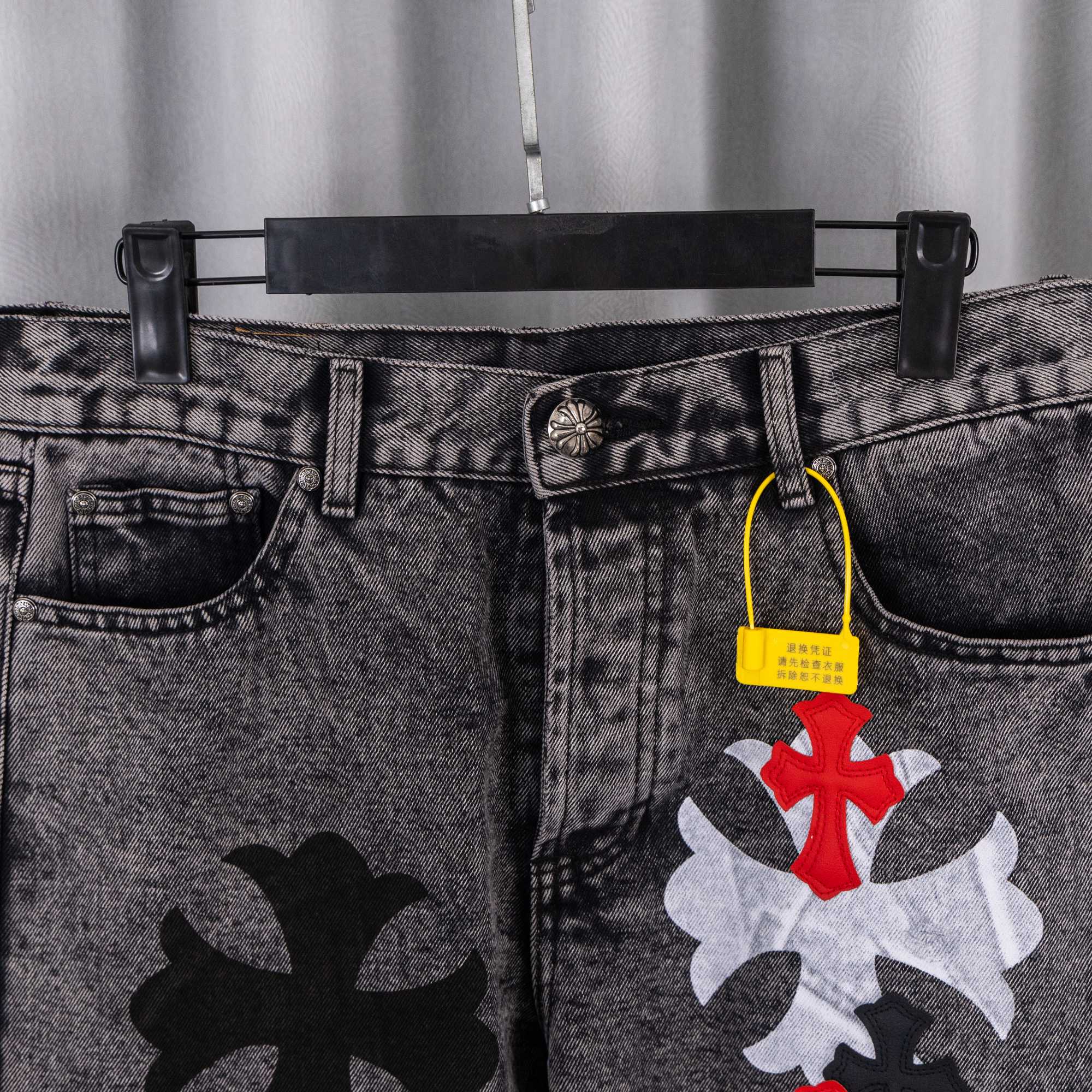 Black denim pants with belt loops, front pockets, and cross patches