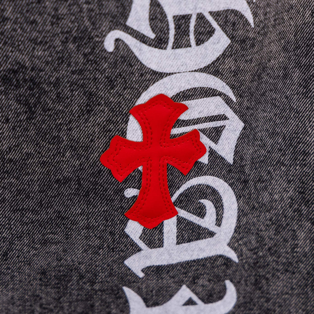 Dark gray denim jeans with red cross patch over black-and-white graphic print