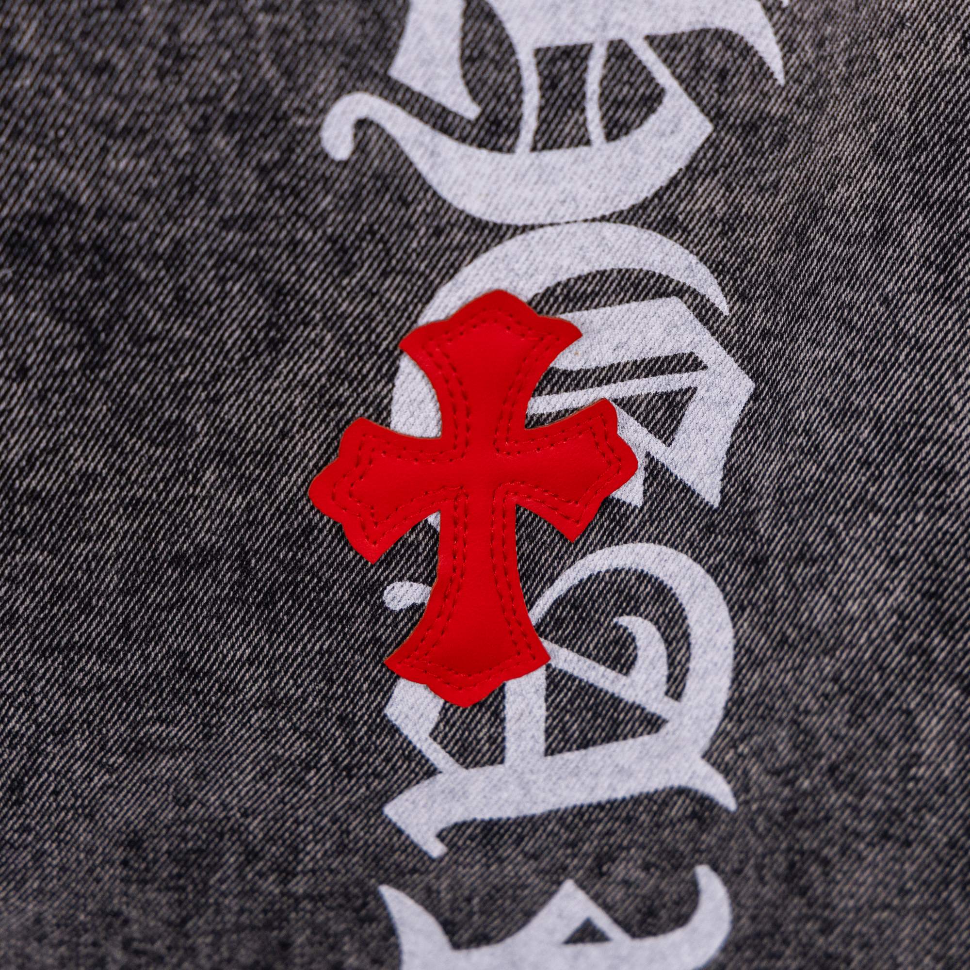 Dark gray denim jeans with red cross patch over black-and-white graphic print