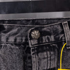 Dark gray denim waistband button and front pocket seam detail with yellow pull