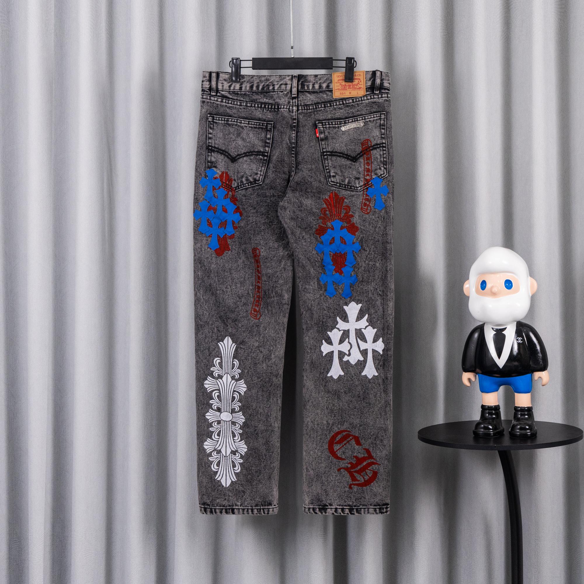 Dark gray denim pants with colorful graphic patches and white motifs on front