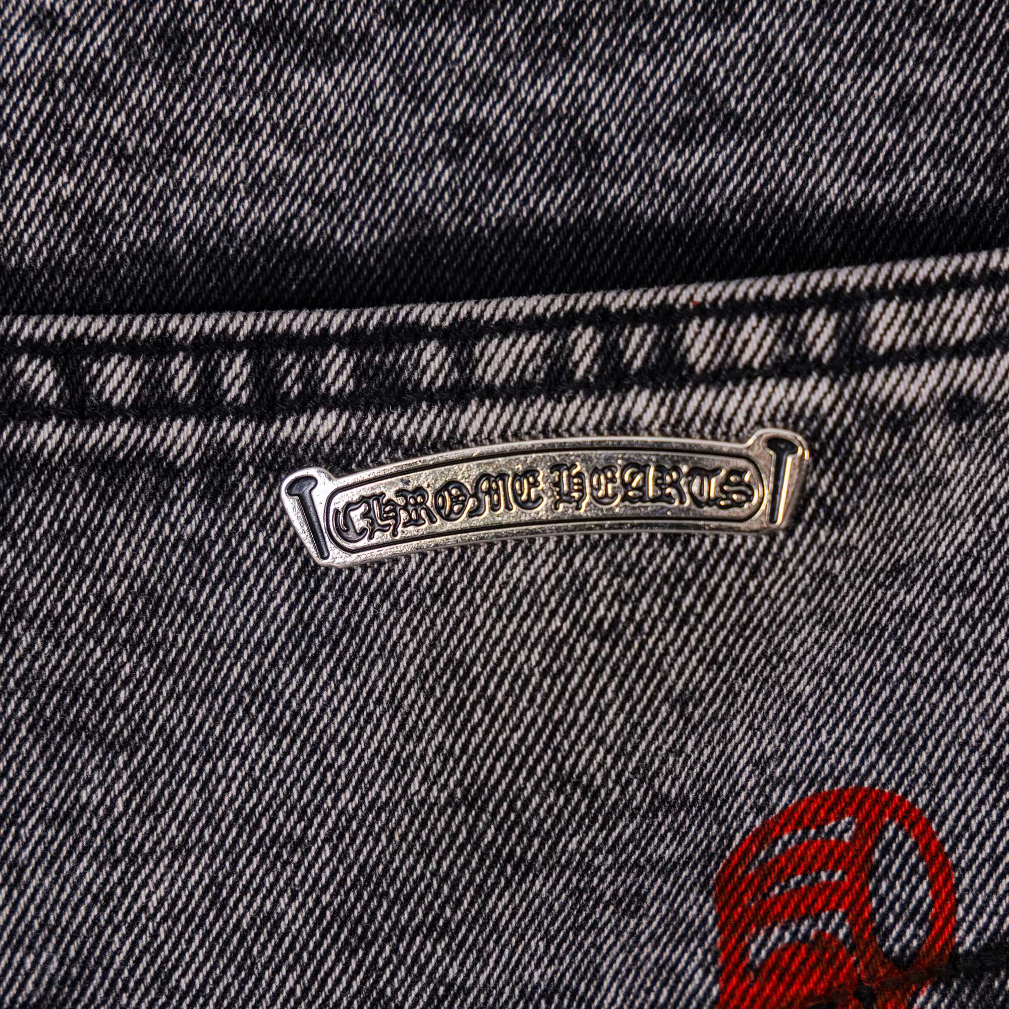 Logo rivet at waistband on dark denim with red emblem patch
