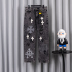 Dark wash denim pants with cross-and-flower patches, front view