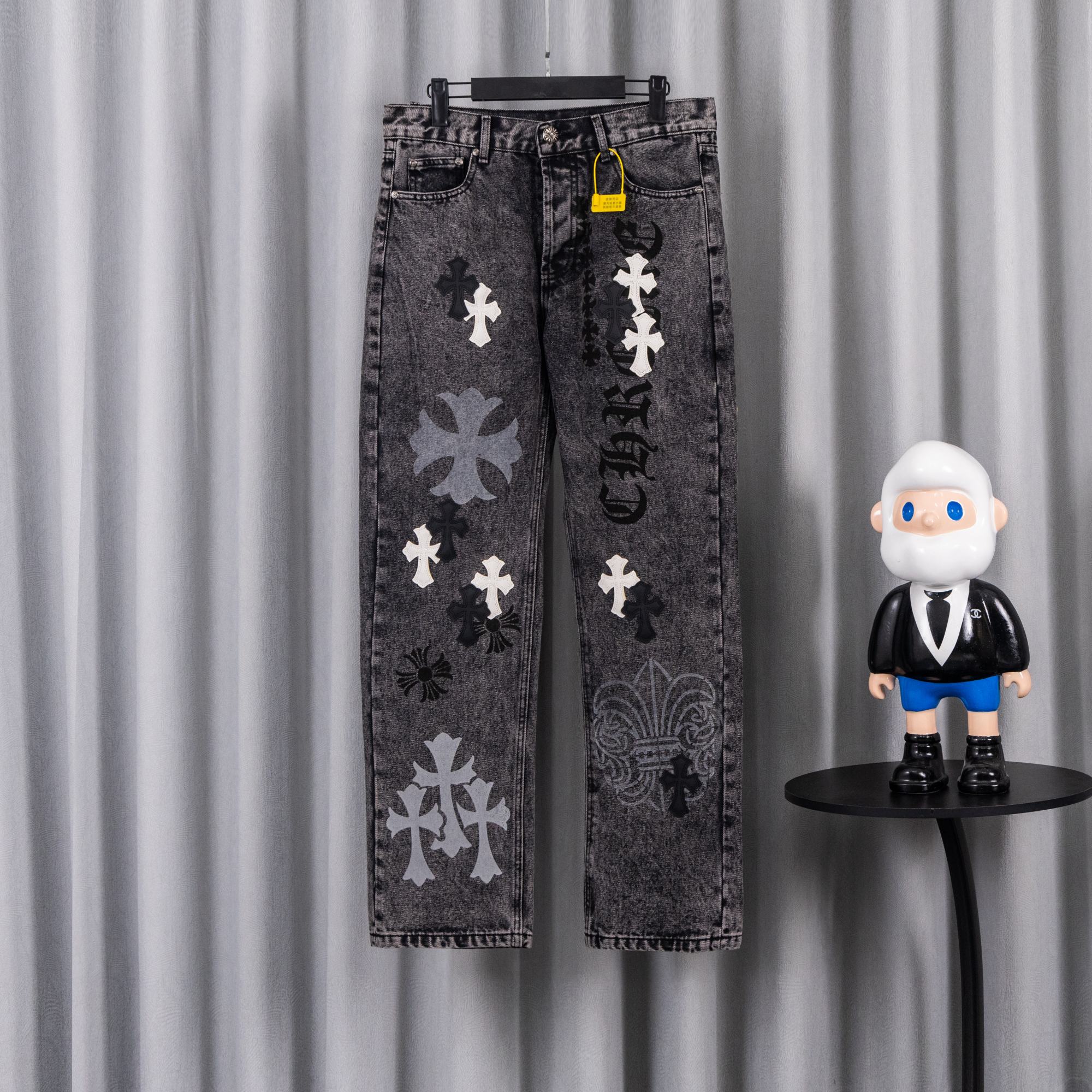 Dark wash denim pants with cross-and-flower patches, front view