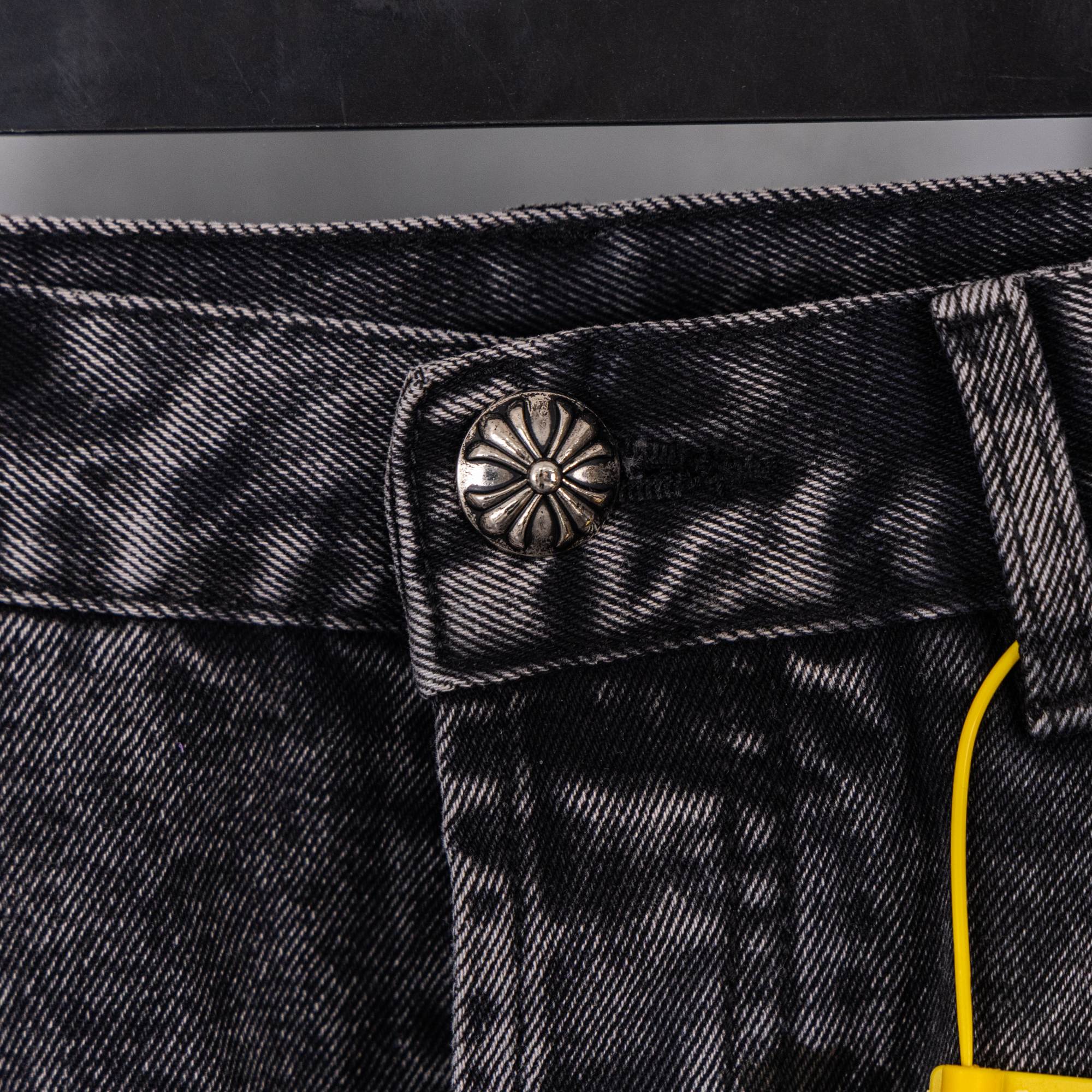 Dark denim pants waistband with decorative button detail and stitched belt loops