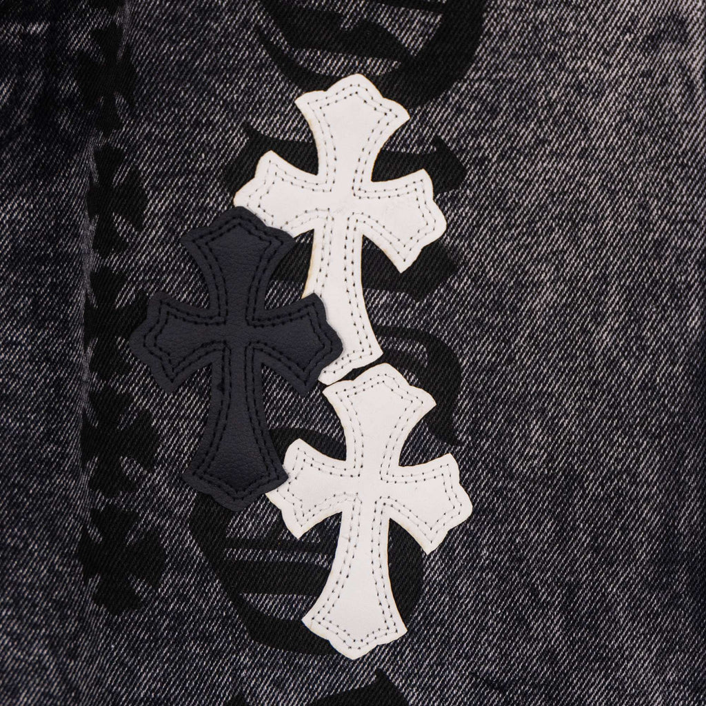 Dark denim pants close-up of white and black cross patch design