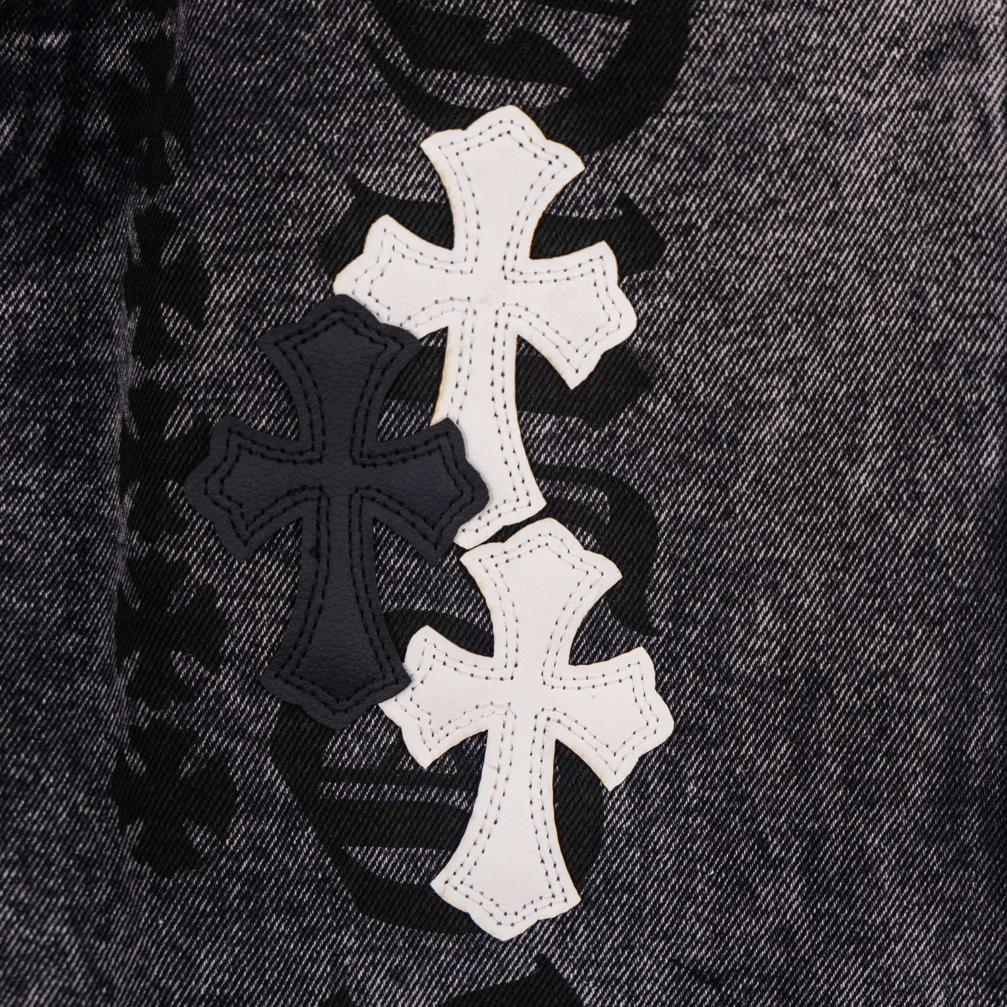Dark denim pants close-up of white and black cross patch design