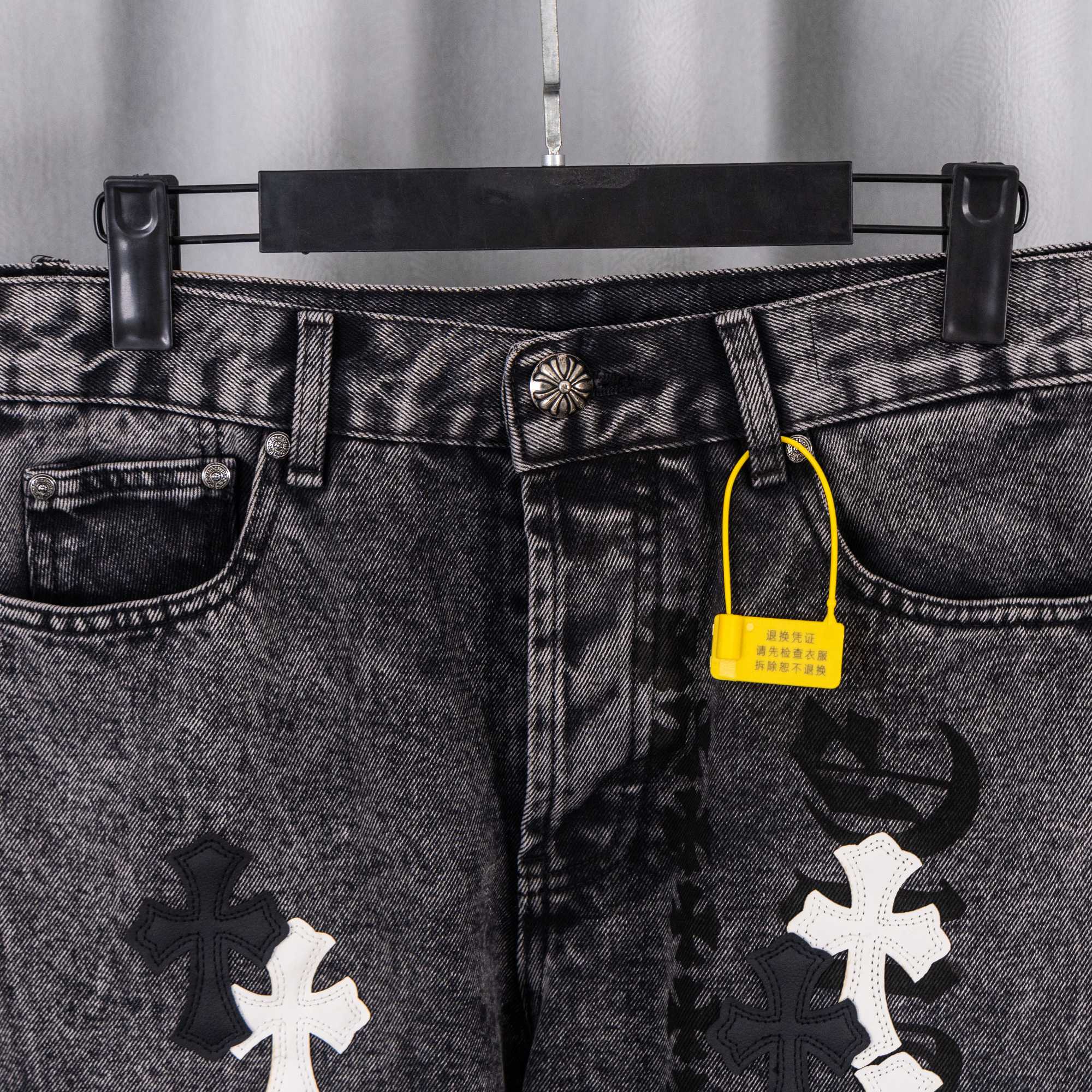Black denim pants with belt loops, button fly, and contrasting cross applique patches