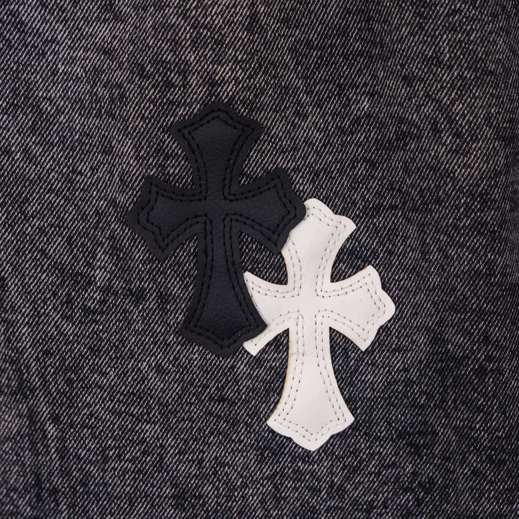 Cross-shaped applique patch on dark denim pants in black and white