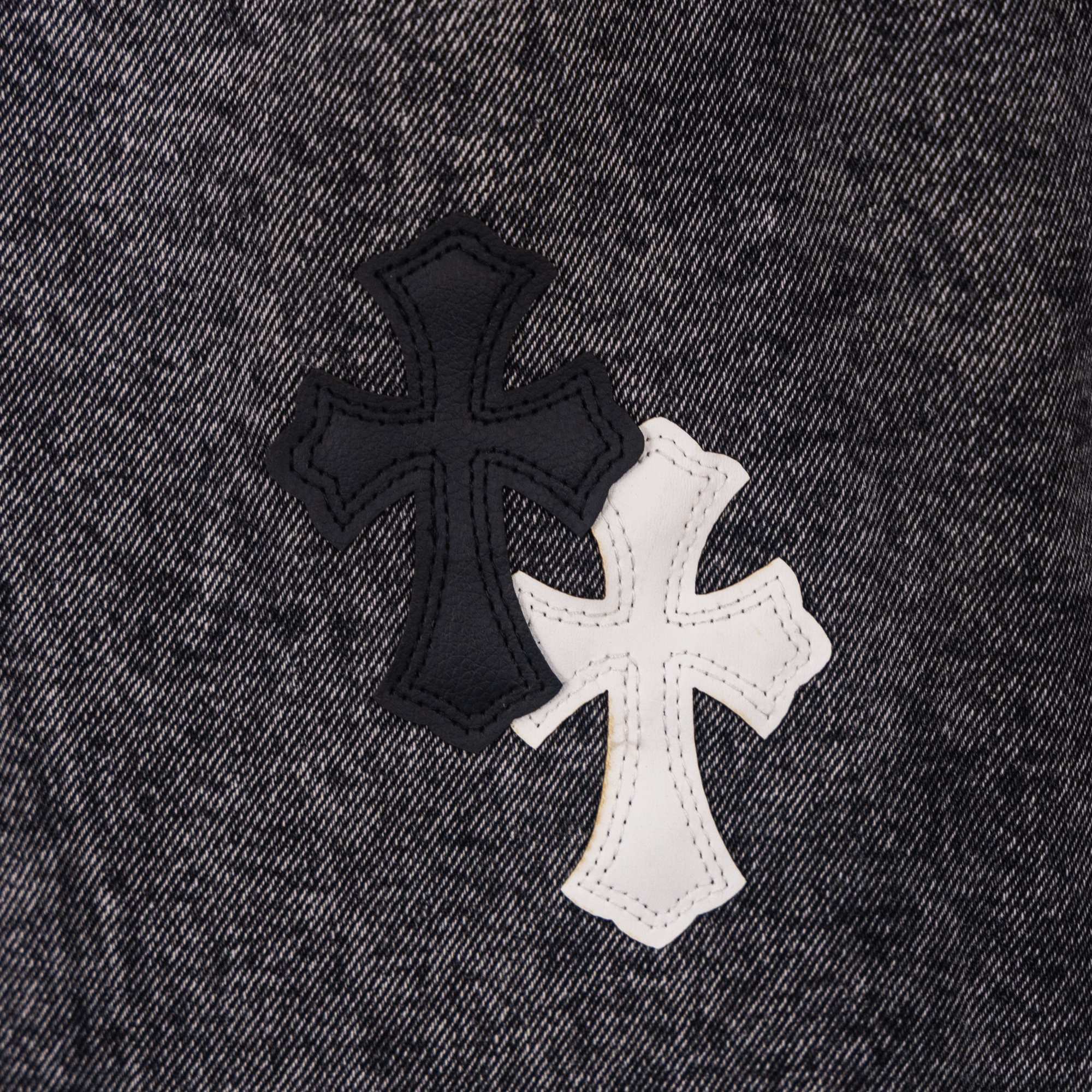 Cross-shaped applique patch on dark denim pants in black and white