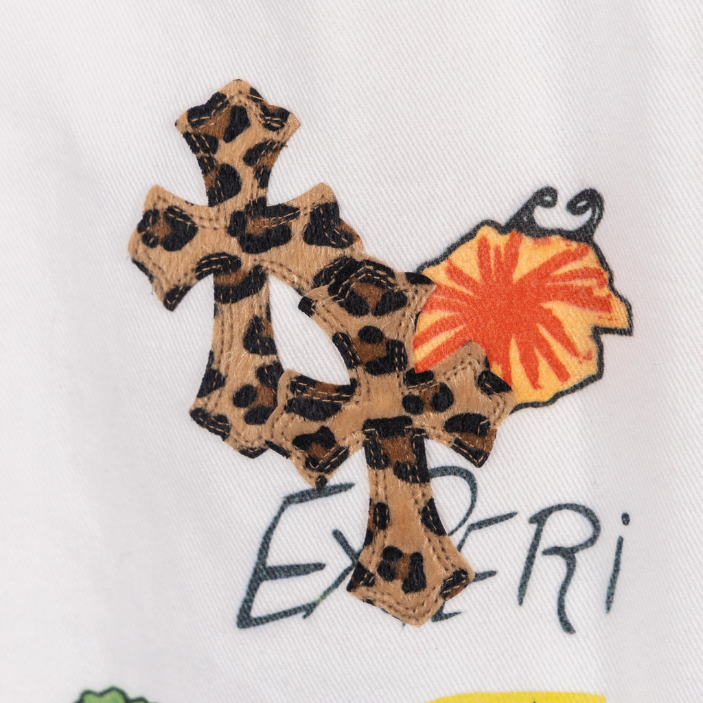 White pants featuring a large leopard-print cross appliqué with orange accent